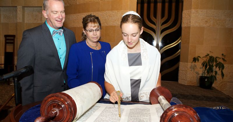 בת מצווה קוראת בתורה עם הוריה